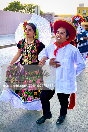 Young Mexican couple in traditional costumes walking in the St Michael Archangel Festival parade in San Miguel de Allende, Mexico