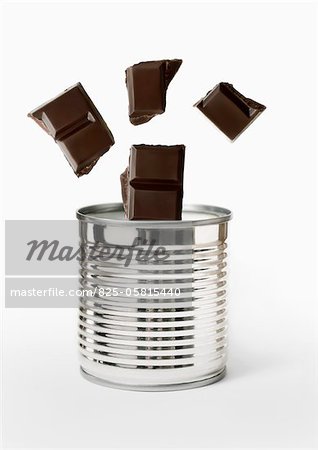 Squares of dark chocolate falling into a can