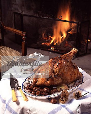 Capon with chestnuts, on table with fireplace