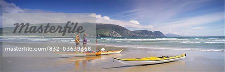 Keel Bay, Achill Island, County Mayo, Ireland; Two People Standing Near Canoes