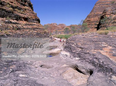 Tourists cross flood scoured rocks, past typical formations, Purnululu National Park, UNESCO World Heritage Site, Bungle Bungle, Kimberley, Western Australia, Australia, Pacific