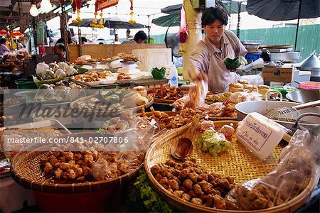 A shopkeeper puts fish cakes on a tray on a stall in the Weekend market in Bangkok, Thailand, Southeast Asia, Asia