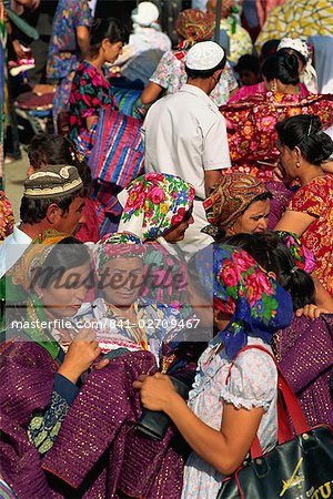 Women in bright dresses and head scarves in the new clothes market within the Old City wall of Bukhara, Uzbekistan, Central Asia, Asia