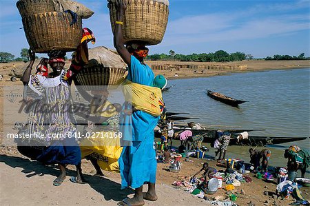 Women with baskets of laundry on their heads beside the river, Djenne, Mali, Africa