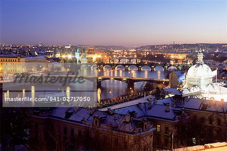 Snow covered bridges across Vltava River dividing Old Town from Mala Strana suburbs in winter twilight, Mala Strana, Prague, Czech Republic, Europe