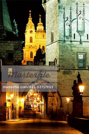 Romanesque and Gothic Malostranske bridge towers, with the two towers of Baroque St. Nicholas church beyond, at night, Mala Strana, Prague, Czech Republic, Europe Romanesque and Gothic Malostranske bridge towers, with the two towers of Baroque St. Nicholas church beyond, at night, Mala Strana, Prague, Czech Republic, Europe