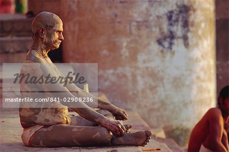 Hindu pilgrim meditating, sitting cross-legged on the Ghats, Varanasi (Benares), Uttar Pradesh State, India