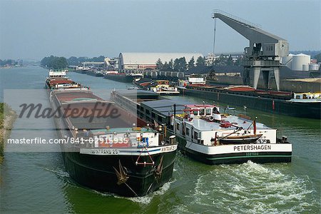 Large barges pass on busy canal near the Netherlands border, northern Germany, Europe