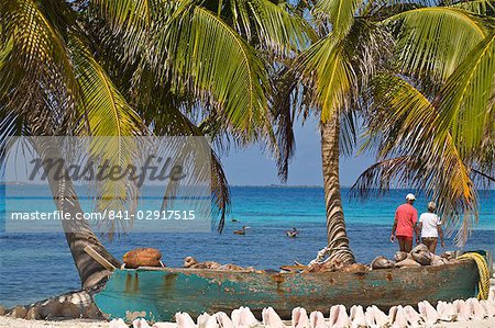 Shells in front of canoe filled with coconut husks, Laughing Bird Caye, Belize, Central America