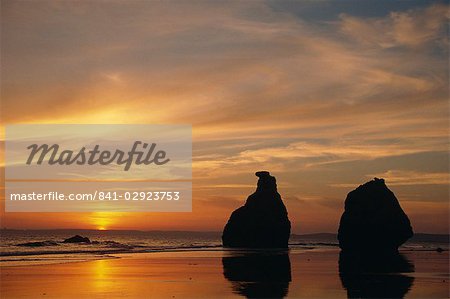 Rocks on the coastline silhouetted at sunset at Praia de Alvor in the Algarve, Portugal, Europe