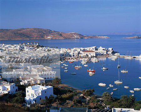 Boats in the harbour and windmills on the coast, with the sea and hills in the background, on Mykonos, Cyclades Islands, Greek Islands, Greece, Europe