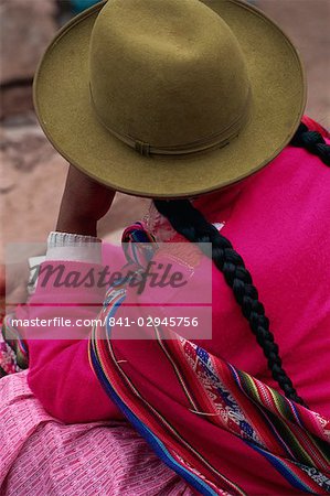 The back of an Indian woman wearing a felt hat and plaited hair in the market at Pisac in the Cuzco area, Peru, South America