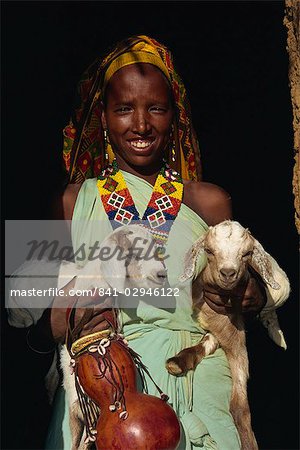 Woman holding twin kid goats and gourd, and wearing beads, Harar, Ethiopia, Africa