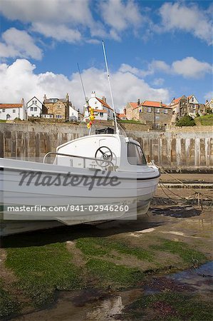 White boat on The Landing in harbour at low tide with Old Bay area of fishing village above coastal defence sea wall behind, Robin Hood's Bay, Yorkshire, England, United Kingdom, Europe