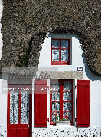 Exterior Of A Thatched Cottage With Red Door And Shutters In La