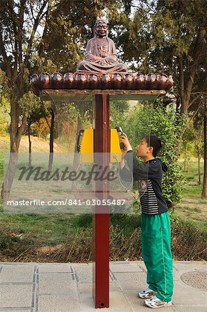 A boy using a monk decorated telephone box at Shaolin temple, birthplace of Kung Fu martial arts, Shaolin, Henan Province, China, Asia