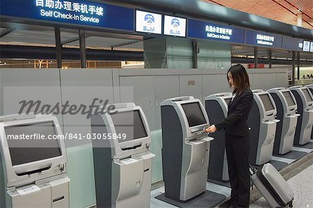 A Chinese business woman using the self service check in machines at Beijing Capital Airport part of new Terminal 3 building opened February 2008, second largest building in the world, Beijing, China, Asia