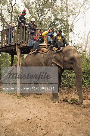 Japanese tourists board the elephant that will take them on safari, at the Island Jungle Resort hotel, Royal Chitwan National Park, Terai, Nepal, Asia
