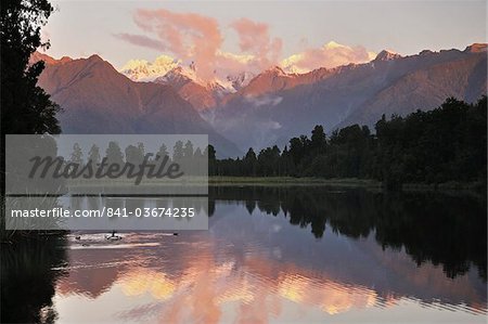 Sunset, Lake Matheson, with Mount Tasman and Mount Cook behind clouds, Westland Tai Poutini National Park, UNESCO World Heritage Site, West Coast, Southern Alps, South Island, New Zealand, Pacific