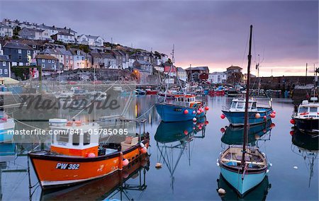 Fishing boats crowd a placid Mevagissey Harbour at dawn, Mevagissey, South Cornwall, England, United Kingdom, Europe Fishing boats crowd a placid Mevagissey Harbour at dawn, Mevagissey, South Cornwall, England, United Kingdom, Europe