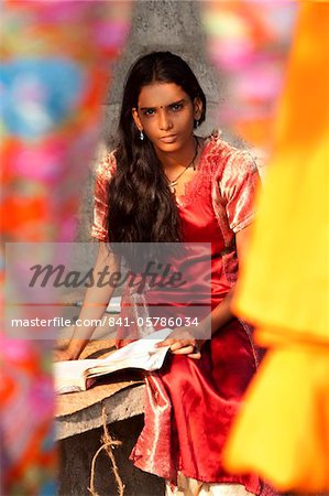 Student girl, sitting behind bright coloured silks, Kerala, India, Asia