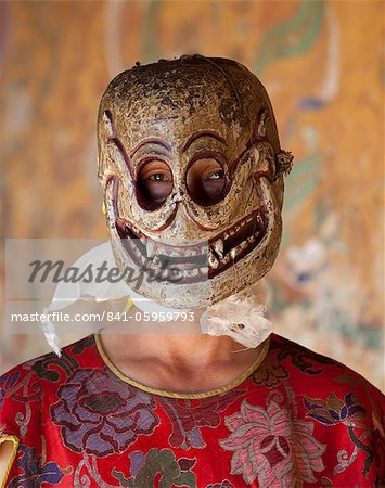 Buddhist monk wearing carved wooden mask in the shape of a skull preparing to take part in traditional dance performance at the Tamshing Phala Choepa Tsechu, near Jakar, Bumthang, Bhutan, Asia