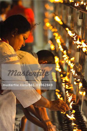 Devotee lighting candles at sunset in the Temple of the Sacred Tooth Relic (Temple of the Tooth), site of Buddhist pilgrimage, Kandy, Sri Lanka, Asia