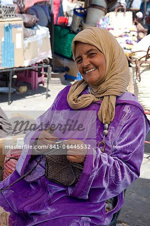 A woman in traditional dress knitting wool hats in the souk, Marrakech, Morocco, North Africa, Africa