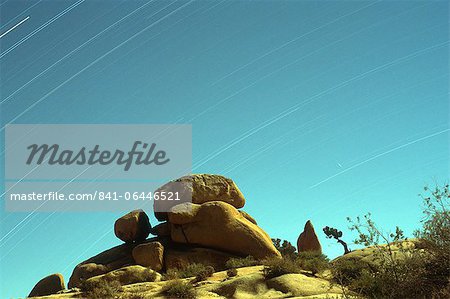 Time exposure of stars streaking across the sky with rock formations in the foreground, Joshua Tree National Park, California, United States of America, North America