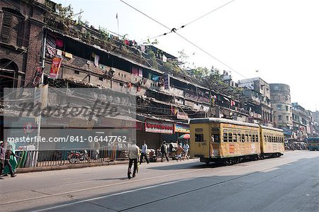 Yellow Kolkata tram passing Kolkata slums in the early morning, Kolkata, West Bengal, India, Asia