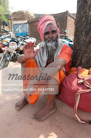 Travelling saddhu dressed in holy colour orange, resting beneath a village tree, Bhubaneshwar, Orissa, India, Asia