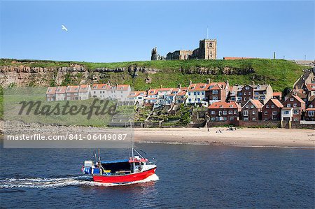 Fishing boat entering the harbour below Whitby Abbey, Whitby, North Yorkshire, Yorkshire, England, United Kingdom, Europe