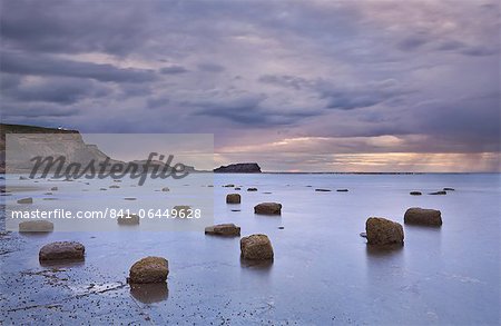 Giant boulders at low tide in Saltwick Bay with showery weather over Saltwick Nab, North Yorkshire, Yorkshire, England, United Kingdom, Europe