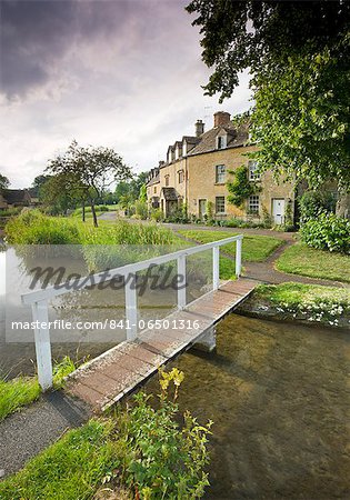 Cottages and footbridge over the River Eye in the Cotswolds village of Lower Slaughter, Gloucestershire, England, United Kingdom, Europe