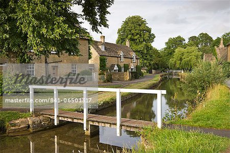 Cottages and footbridge over the River Eye in the Cotswolds village of Lower Slaughter, Gloucestershire, England, United Kingdom, Europe
