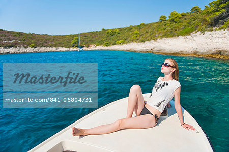Tourist sunbathing on a boat in the Pakleni Islands (Paklinski Islands), Hvar Island, Dalmatian Coast, Adriatic Sea, Croatia, Europe