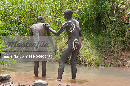 Before the Donga stick fight, the Surma warriors apply a body paint made of clay and mineral on their bodies, Surma tribe, Tulgit, Omo River Valley, Ethiopia, Africa