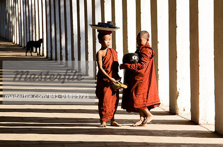 Novice Buddhist monks collecting alms, standing in the shadows of columns at Shwezigon Paya, Nyaung U, Bagan, Myanmar (Burma), Asia