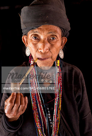 Woman of the <b>Ann tribe</b> in traditional black dress and colourful beads ... - 841-06805765em-Woman-of-the-Ann-tribe-in-traditional-black-dress-and-colourful-beads-smoking-a-pipe-in-the-doorway-of-her-home-in-a