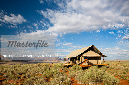 One of the luxury tents set in a magnificent landscape of orange sand dunes and sandstone mountains at Wolwedans Dune Camp in the Namib Rand game reserve, Namib Naukluft Park, Namibia, Africa