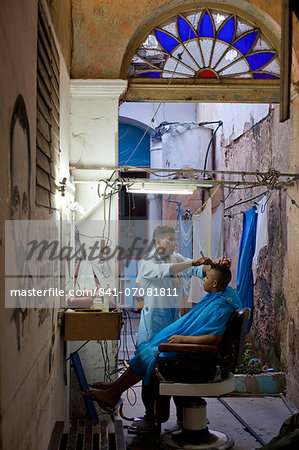 Man having haircut in backstreet barber shop, Havana Viejo, Havana, Cuba, West Indies, Central America