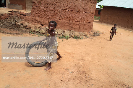 African girl having fun rolling an old tyre, Tori, Benin, West Africa, Africa