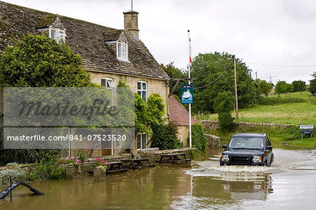 Four wheel drive car drives through flooded road in Swinbrook, Oxfordshire, England, United Kingdom