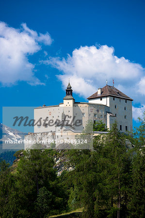 Tarasp Castle surrounded by larch forest in the Lower Engadine Valley, Switzerland, Europe