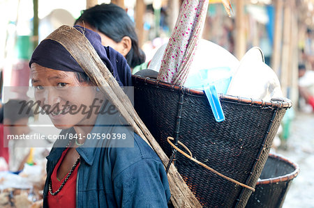 Smiling Naga woman wearing traditional woven cane head basket, shopping in Tizit village weekly local market, Nagaland, India, Asia