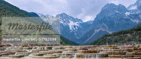 A panoramic view of cascading waterfalls and mountain backdrop, including Yu Long Xue Shan at White Water River (Baishuihe), Lijiang, Yunnan, China, Asia