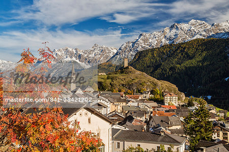 Autumn colors frame the village of Ardez surrounded by woods and snowy peaks, Engadine, Canton of Graubunden, Switzerland, Europe