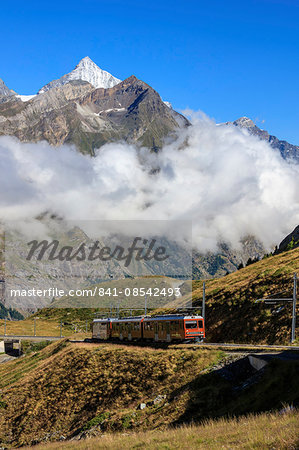 The red Bahn train proceeds with the peak of Dent Herens in the background, Gornergrat, Canton of Valais, Swiss Alps, Switzerland, Europe