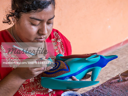 Woman painting a colorful carved wooden figure (alebrije) of a wolf, Oaxaca area, Mexico, North America