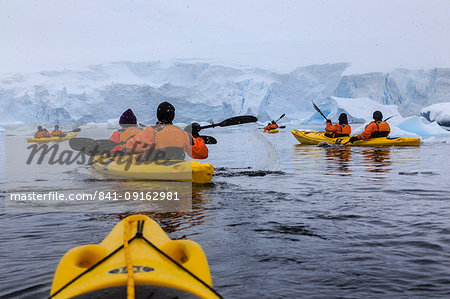 Expedition tourists kayaking in cold, snowy weather, with icebergs, Chilean Gonzalez Videla Station, Waterboat Point, Antarctica, Polar Regions